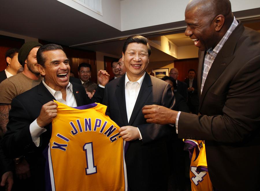 Xi Jinping (c-frente) recibe una camiseta de recuerdo de Los Ángeles Lakers con su nombre impreso de parte del exjugador de los Lakers Magic Johnson (d-frente) en el Staples Center en Los Ángeles, Estados Unidos, el 17 de febrero de 2012. (Xinhua/Lan Hongguang)