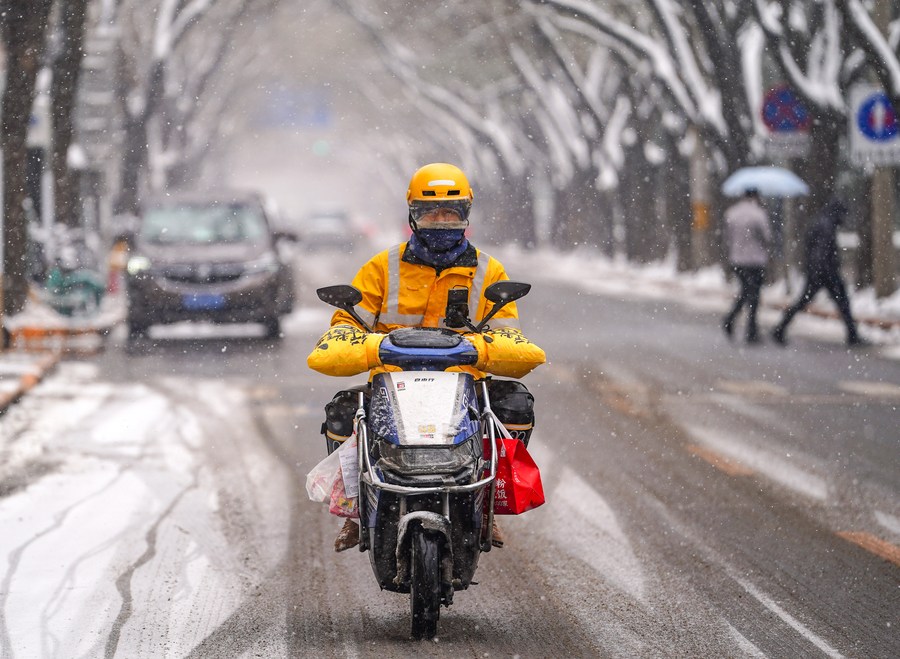 La foto tomada el 13 de diciembre de 2023 muestra a un repartidor que monta en la nieve en la avenida Yangfangdian Oeste en Beijing, capital de China. (Xinhua/Chen Yehua)