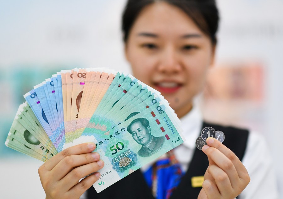 Una empleada bancaria muestra los billetes y monedas de la edición de 2019 de la quinta serie de renminbi (RMB o yuan, la moneda china) en una sucursal del Banco Industrial y Comercial de China (ICBC, siglas en inglés) en la capital china, Beijing, el 30 de agosto de 2019. (Xinhua/Chen Yehua)