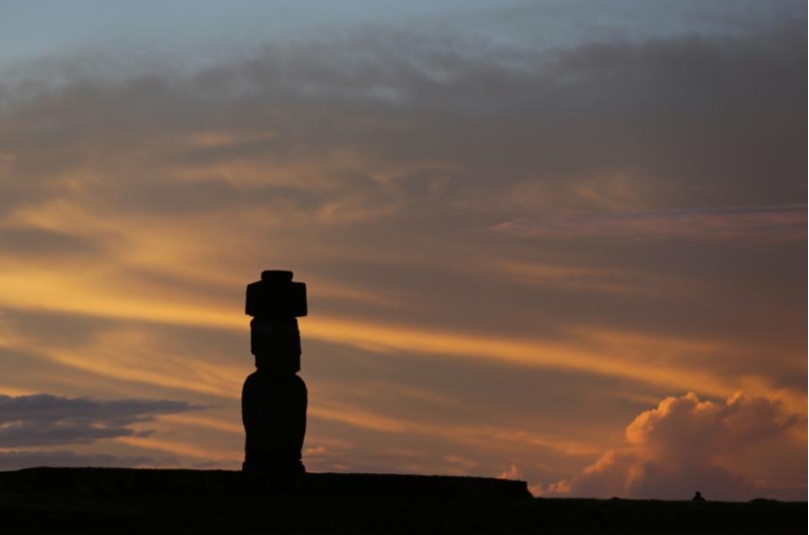 Imagen del 7 de julio de 2018 de la vista de la puesta del sol detrás de una de las estatuas moai, en el sitio arqueológico de Ahu Tahai, cerca de Hanga Roa, capital de la Isla de Pascua, Chile. (Xinhu/Wang Pei) 