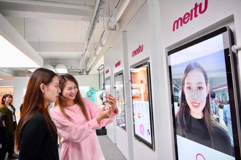 Unas empleadas toman una foto con la aplicación de Meitu en la sala de exhibiciones de la compañía en Xiamen, en la provincia oriental china de Fujian, el 10 de noviembre de 2020. (Xinhua/Jiang Kehong)