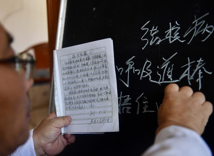Un médico escribe información sobre la prevención de la tuberculosis en el tablero de anuncios sanitarios de su clínica en la aldea de Yangang, del distrito de Yudu, en la provincia oriental china de Jiangxi, el 15 de agosto de 2023. (Xinhua/Hu Chenhuan)