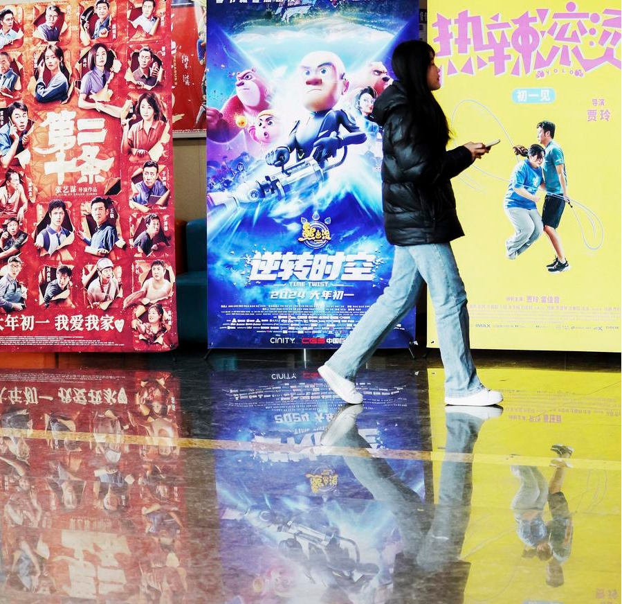 Una mujer camina frente a afiches de películas en un cine en el distrito de Tancheng, en la ciudad de Linyi, provincia de Shandong, en el este de China, el 15 de febrero de 2024. (Xinhua/Zhang Chunlei)