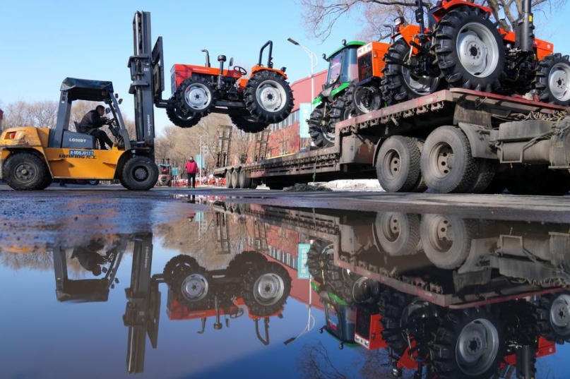 Un empleado opera un montacargas para cargar un tractor en un camión en una compañía de fabricación de tractores en Jiamusi, provincia de Heilongjiang, en el noreste de China, el 12 de marzo de 2024. (Xinhua/Wang Jianwei)