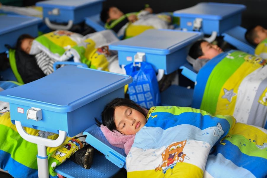 Niños de tercer grado toman la siesta durante el descanso de mediodía utilizando sillas plegables en una escuela primaria de la ciudad de Liuyang, en la provincia central china de Hunan, el 10 de enero de 2024. (Xinhua/Chen Zeguo)