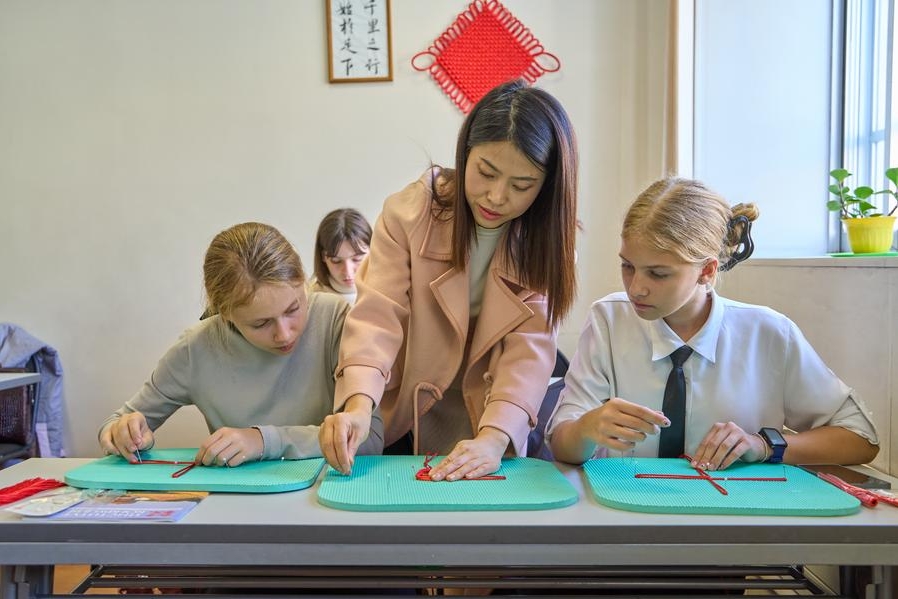 Imagen del 26 de octubre de 2023 de una artesana china (C) enseñando a los estudiantes a hacer nudos chinos durante la Semana de Cultura y Turismo de Jilin en el Instituto Confucio de la Universidad Federal del Lejano Oriente de Rusia. (Xinhua/Guo Feizhou)