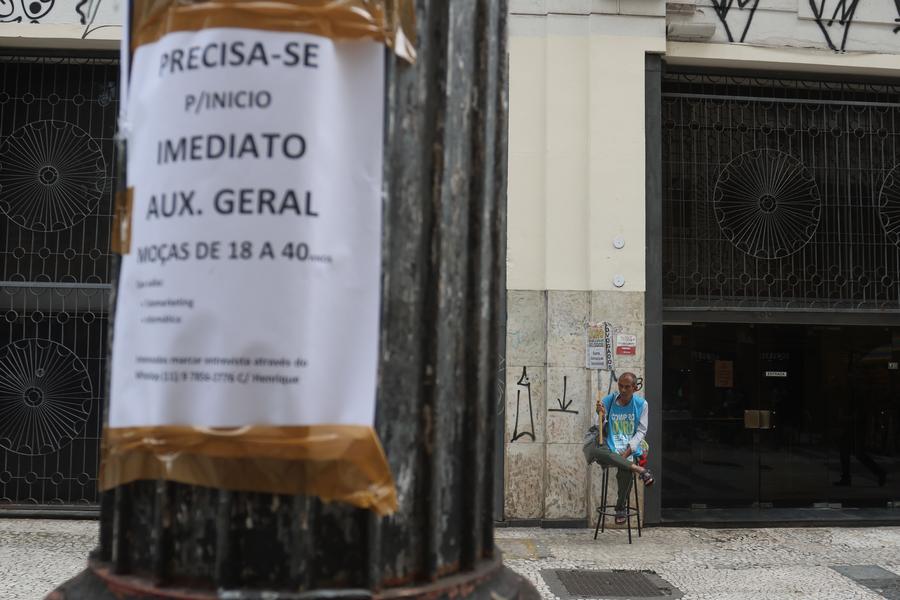 Un hombre trabaja sosteniendo un cartel frente a un poste con un anuncio de ofertas de empleo, en Sao Paulo, Brasil, el 31 de enero de 2024. (Xinhua/Rahel Patrasso) 