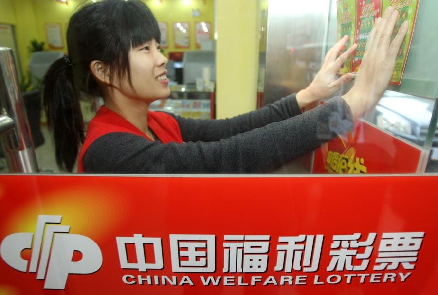 Una empleada coloca carteles en un local de venta de lotería en Nantong, ciudad de la provincia oriental china de Jiangsu. (Xinhua/Xu Congjun)