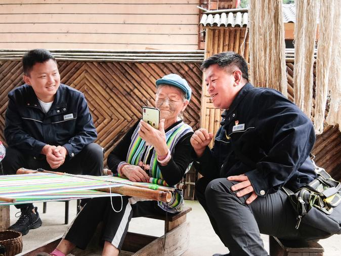 La foto de archivo, tomada el 16 de septiembre de 2022, muestra a Li Wenshi (centro) aprendiendo navegación por internet en un teléfono móvil en la aldea Dizhengdang del poblado de Dulongjiang, distrito autónomo de las etnias drung y nu de Gongshan, en la provincia suroccidental china de Yunnan. (Xinhua)