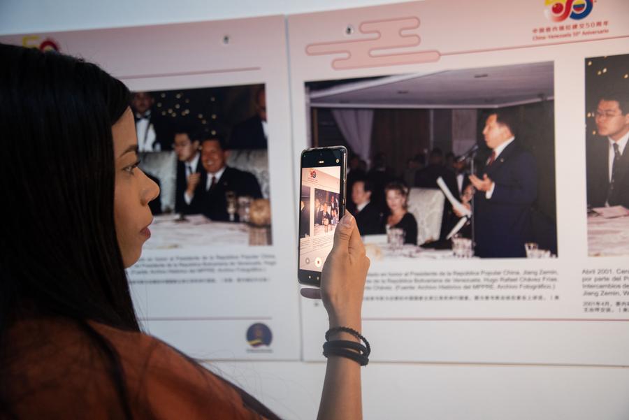 Una mujer toma una fotografía con su teléfono móvil durante la exposición fotográfica "A Toda Prueba y Todo Tiempo" en el marco del 50 Aniversario de las Relaciones Diplomáticas entre China y Venezuela en el Museo de Bellas Artes, en Caracas, Venezuela, el 26 de junio de 2024. (Xinhua/Marcos Salgado) 