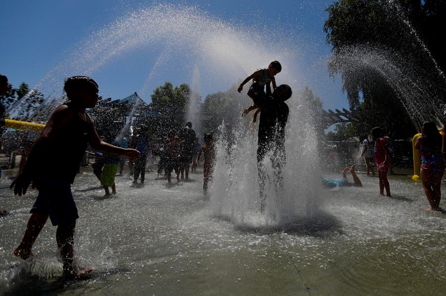 Imagen del 22 de junio de 2024 de personas refrescándose en una fuente, en el Condado de Orange, California, Estados Unidos. (Xinhua)