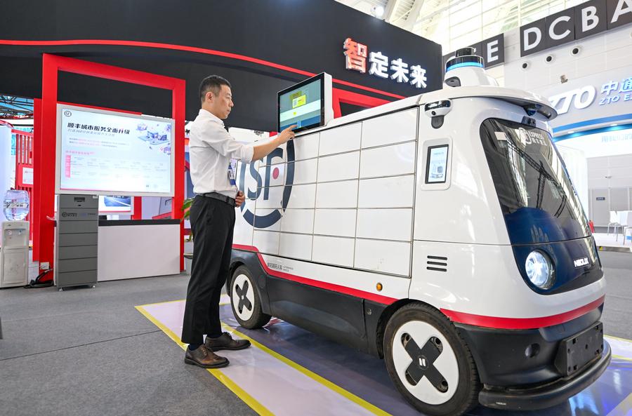 Imagen del 20 de junio de 2024 de un expositor operando un vehículo de entrega autónomo no tripulado para un servicio de mensajería presentado en la Exposición Mundial de Inteligencia 2024, en Tianjin, en el norte de China. (Xinhua/Sun Fanyue) 