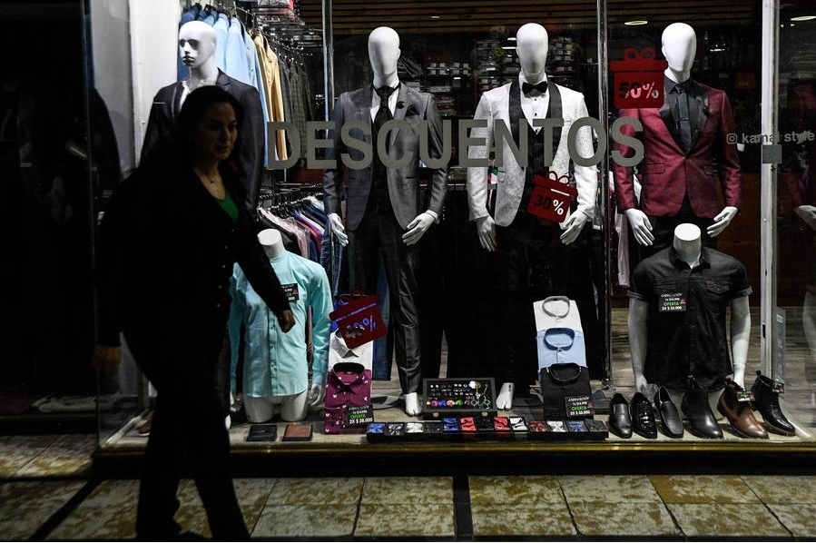 Una mujer camina frente a una tienda de ropa, en Santiago, capital de Chile, el 11 de abril de 2024. (Xinhua/Jorge Villegas)