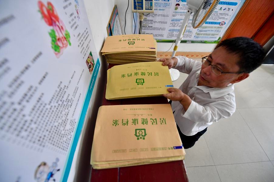 Un médico ordena los registros de salud de los aldeanos en su clínica en la aldea de Yangang, en el distrito de Yudu de la provincia oriental china de Jiangxi, el 16 de agosto de 2023. (Xinhua/Hu Chenhuan)