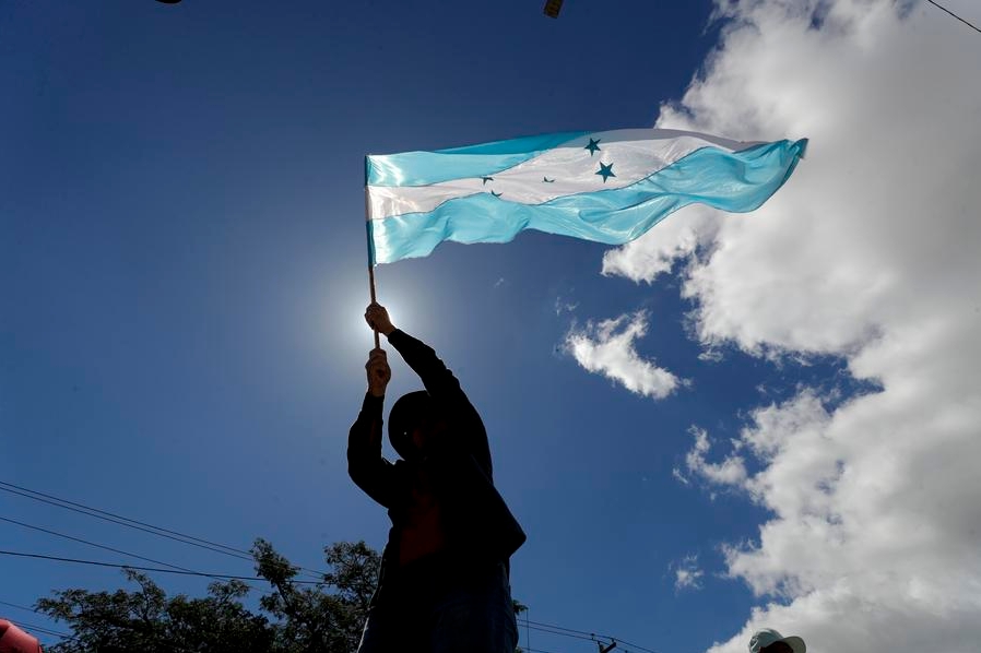 Un hombre sostiene una bandera nacional hondureña mientras asiste a un acto conmemorativo por el segundo aniversario del mandato de la presidenta hondureña, Xiomara Castro, en Tegucigalpa, Honduras, el 27 de enero de 2024. (Xinhua/Rafael Ochoa)