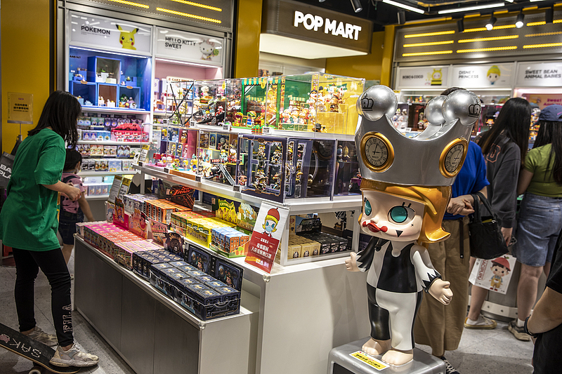 Una mujer revisa una caja sorpresa frente a una máquina expendedora Pop Mart en Shanghai el 23 de diciembre de 2020. [Foto/VCG]