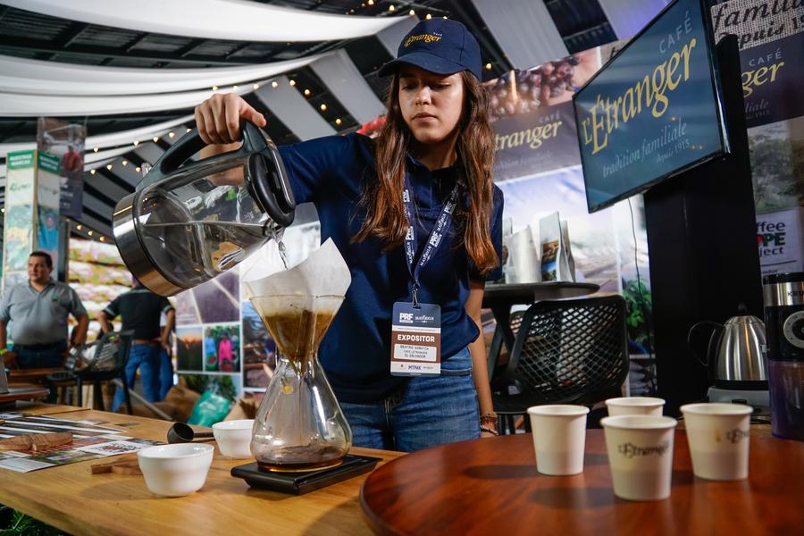 Una comerciante de café prepara una bebida durante la sexta edición del Foro de Productores y Tostadores de Café, en Nuevo Cuscatlán, en el departamento de La Libertad, El Salvador, el 16 de marzo de 2023. (Xinhua/Alexander Peña)