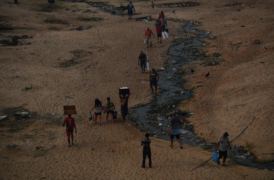 Personas caminan por un área a orillas del río Negro afectada por el humo que cubre la ciudad durante la sequía, en Manaos, en el estado de Amazonas, Brasil, el 13 de octubre de 2023. (Xinhua/Lucio Tavora)