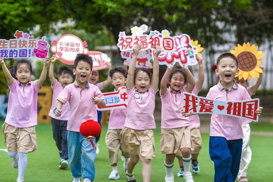 Niños corren con carteles festivos y de buenos deseos en un jardín infantil en la ciudad de Xinghua, en la provincia oriental china de Jiangsu, el 26 de septiembre de 2024. (Xinhua/Zhou Shegen)