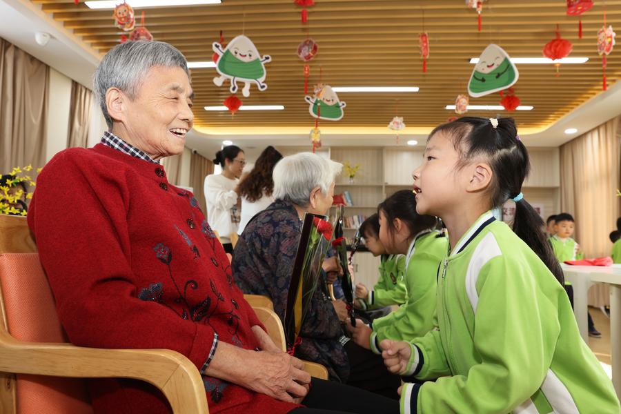 Niños dan palmadas en las piernas de los ancianos en un centro de atención a personas mayores, en el distrito de Deqing de la ciudad de Huzhou, en la provincia de Zhejiang, en el este de China, el 10 de octubre de 2024. (Xinhua/Ni Lifang) 