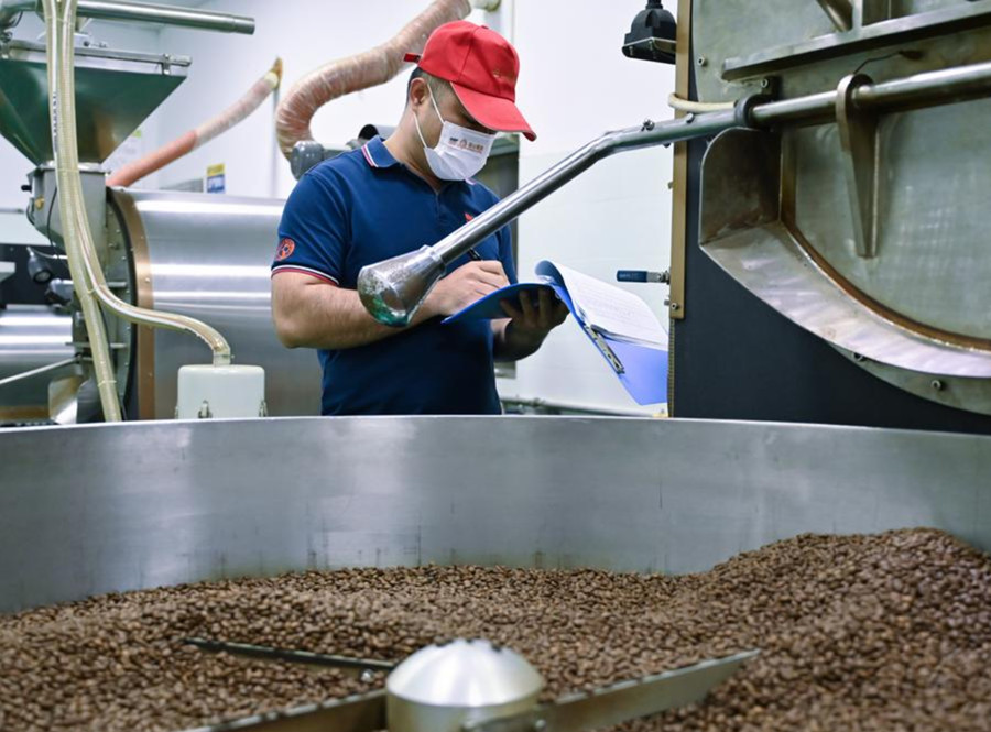 Un empleado trabaja en el taller de tostado de una empresa cafetalera en el distrito autónomo de las etnias li y miao de Qiongzhong, en la provincia sureña china de Hainan, el 9 de enero de 2024. (Xinhua/Fan Yuqing)