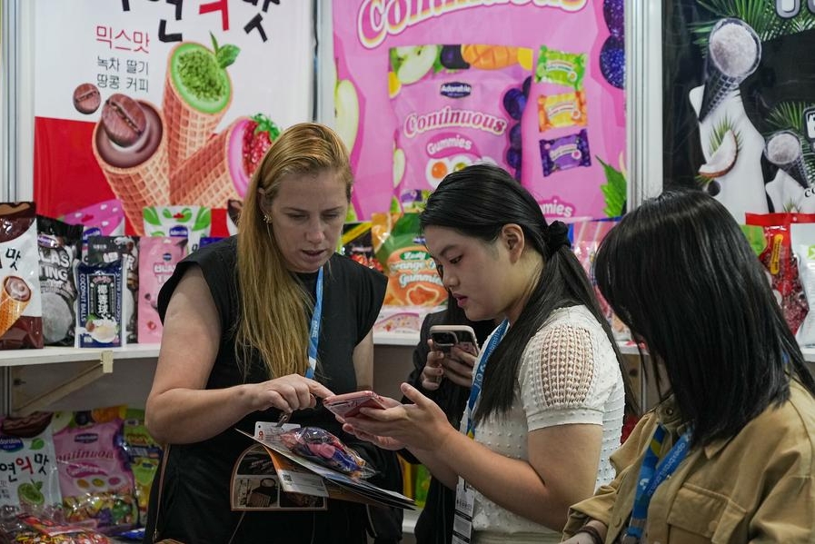 Imagen del 9 de abril de 2025 de una vendedora interactuando con una visitante en la feria internacional de alimentos y bebidas "Anuga Select Brasil", en Sao Paulo, Brasil. (Xinhua/Paulo Lopes)