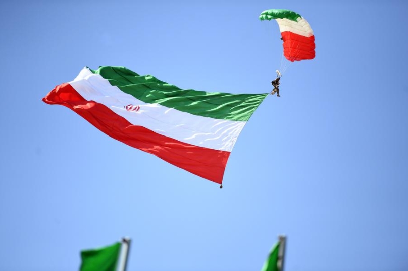 Un paracaidista sostiene una bandera iraní durante el desfile por el Día del Ejército, en Teherán, capital de Irán, el 18 de abril de 2025. (Xinhua/Shadati) 