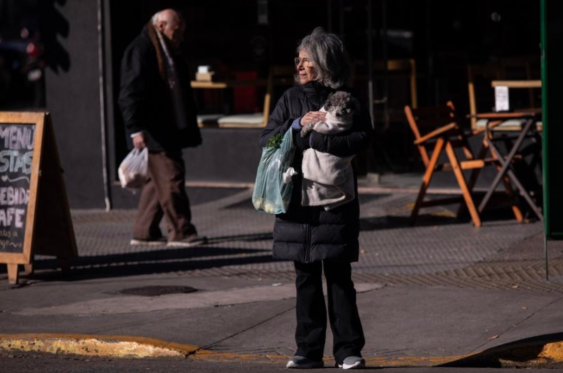 Una mujer porta ropa abrigadora mientras sostiene a su perro en brazos en una calle durante una ola de frío, en la ciudad de Buenos Aires, Argentina, el 25 de mayo de 2024. (Xinhua/Martín Zabala)