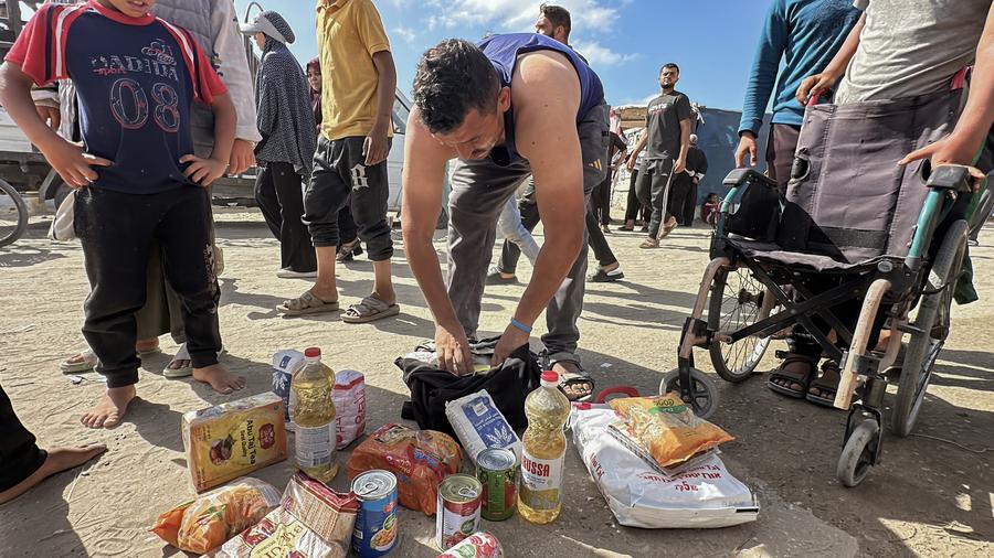 Imagen tomada con un teléfono móvil el 27 de mayo de 2025 de palestinos tras recibir ayuda humanitaria de un centro de distribución, en Rafah, en el sur de la Franja de Gaza. (Xinhua/Rizek Abdeljawad) 