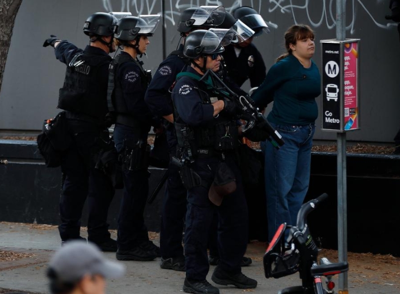 Imagen del 11 de junio de 2025 de una manifestante siendo arrestada, en Los Angeles, Estados Unidos. Casi 400 personas en las protestas sobre inmigración han sido arrestadas o detenidas por el Departamento de Policía de Los Angeles desde el sábado, según medios.  (Xinhua/Qiu Chen)