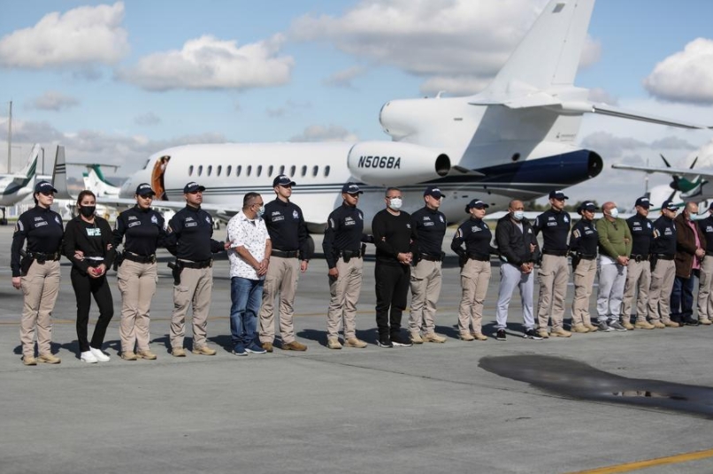 Nini Johana Usuga, alias "La Negra" (2-i), es custodiada por agentes de la Interpol previo a ser extraditada a Estados Unidos por acusaciones de narcotráfico y lavado de dinero, en el aeropuerto militar de Catam, en Bogotá, Colombia, el 1 de julio de 2022. (Xinhua/Jhon Paz)