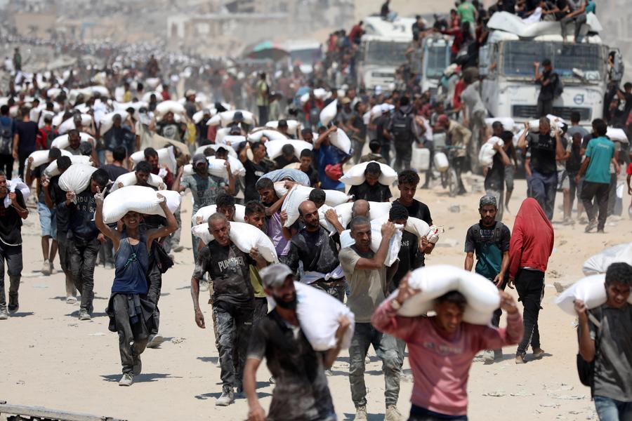 Imagen del 27 de julio de 2025 de palestinos cargando sacos de harina después de que la ayuda humanitaria entrara en Gaza a través de un paso fronterizo, en Beit Lahia, en el norte de la Franja de Gaza. (Xinhua/Rizek Abdeljawad) 
