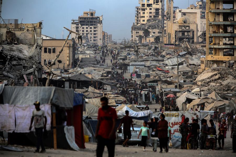 Imagen del 10 de agosto de 2025 de personas caminando frente a tiendas de campaña para palestinos desplazados cerca de una playa, en la Ciudad de Gaza. (Xinhua/Rizek Abdeljawad) 