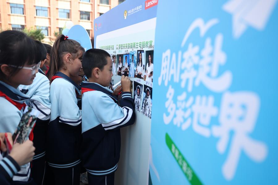 Un niño firma con su nombre en una imagen generada por IA de su profesión soñada en la escuela Yanchuan del distrito de Zhangxian, ciudad de Dingxi, en la provincia noroccidental china de Gansu, el 10 de septiembre de 2025. (Xinhua/Chen Bin)