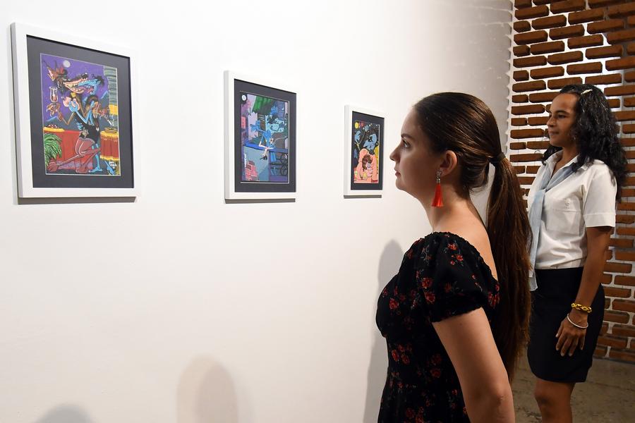 Mujeres observan pinturas realizadas por el cineasta y pintor cubano, Juan Padrón, exhibidas en una galería en el marco de la celebración del 65º aniversario del establecimiento de relaciones diplomáticas entre China y Cuba, en el Barrio Chino de la Habana, en La Habana, capital de Cuba, el 24 de septiembre de 2025. (Xinhua/Joaquín Hernández)