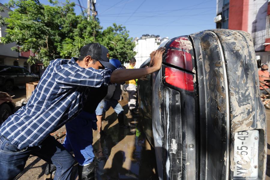 Personas voltean un vehículo afectado por las lluvias, en la ciudad de Poza Rica, en el estado de Veracruz, México, el 12 de octubre de 2025. (Xinhua/Francisco Cañedo) 