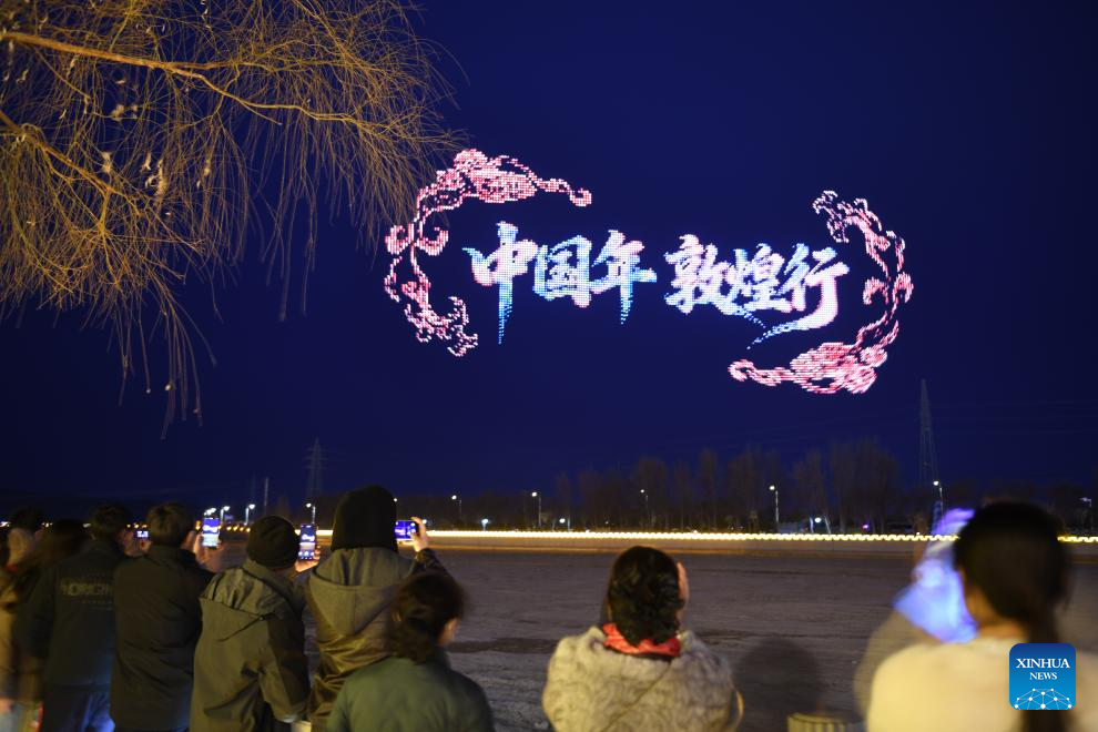 Personas observan espectáculo de drones en un punto escénico en Dunhuang, Gansu