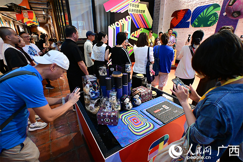 (Foto: Visitantes toman fotos de varios productos de brocado zhuang. Diario del Pueblo digital / Lei Qijun)