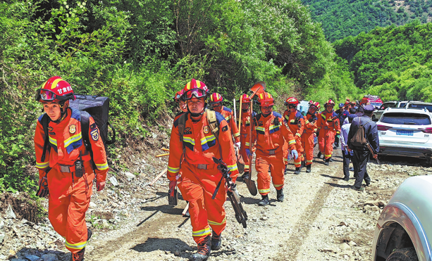 Miembros del equipo de rescate caminan hacia el sitio del deslizamiento después de que el acceso fuera bloqueado por los escombros en el deslizamiento de tierra en Longnan, provincia de Gansu, 7 de julio del 2026. (Foto: Xinhua)