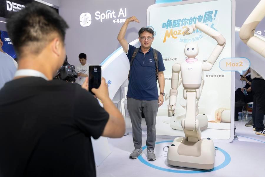 Un visitante y un robot humanoide forman la figura de un corazón mientras posan para fotografías durante la Conferencia Mundial de Inteligencia Artificial (IA) y la Reunión de Alto Nivel sobre Gobernanza Global de la IA 2026, en Shanghai, en el este de China, el 20 de julio de 2026. (Xinhua/Wang Xiang) 